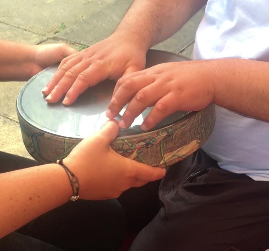 staff member holds rain drum while student touches the surface