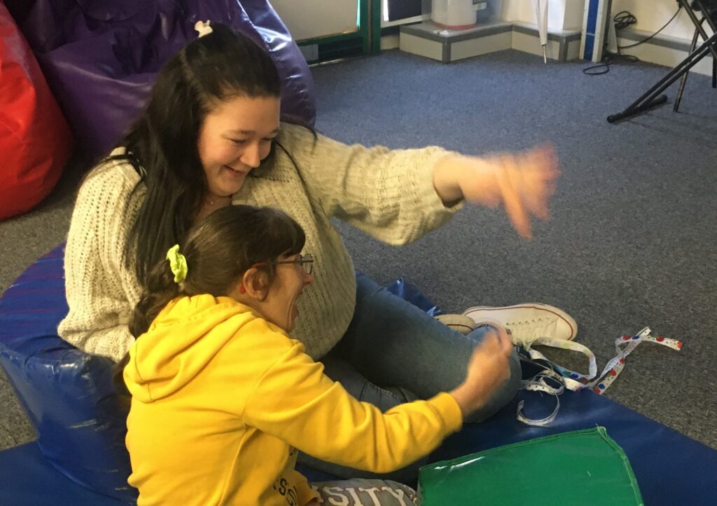 A staff member shows a student the makaton sign for jellyfish
